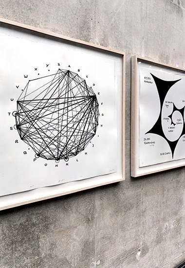 zwei Infografiken in Rahmen, aufgehängt an einer Betonwand